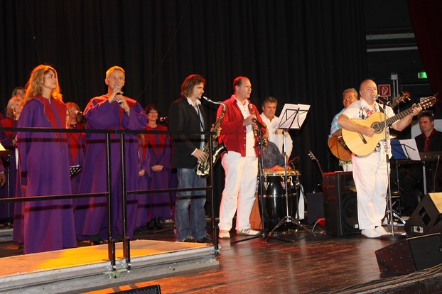 salsa band "Tumbao". Kai Heumann with saxophonist Jens Streifling of the Cologne band "Die Höhner" and the Living Gospel Choir. The choir is dressed in purple.